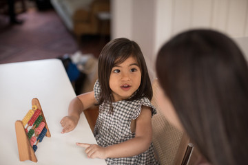Girl using abacus to count with Mother