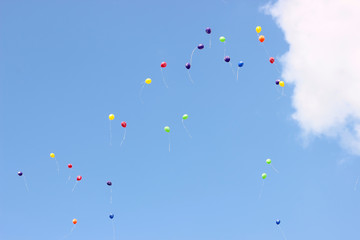 Balloons. The children released a lot of balls with ropes in the sky. Balloons in the blue sky in the rays of the sun.