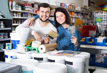 couple demonstrating tools for house renovating in paint store