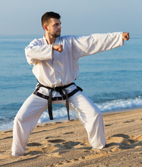 Guy practising karate at seaside