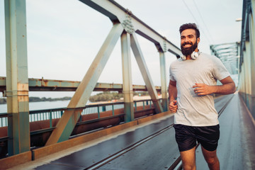 Handsome young happy man running across bridge