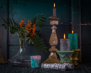 Rough autumn still life with three old candlesticks and branch of rowan