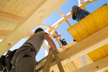 Roof builders mounting prefabricated wooden roof construction. Construction industry concept.