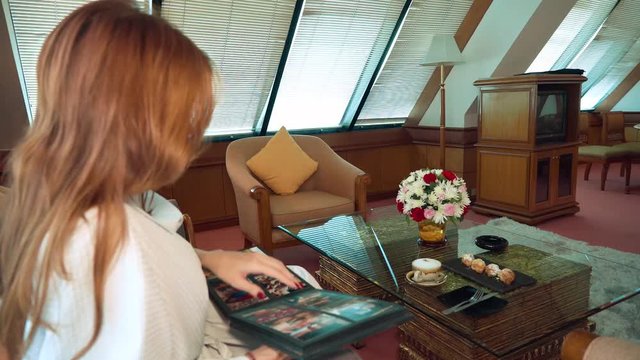 Young woman in bathrobe sitting on couch looking through photo album