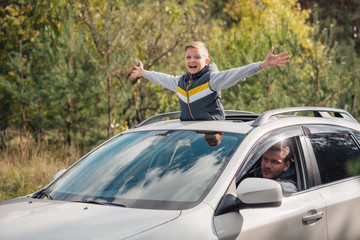 boy standing in car sunroof