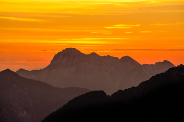 Spectacular mountains silhouettes in orange sunset twilight. Julian Alps, Slovenia.