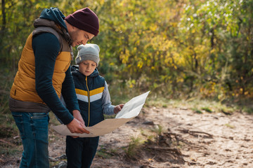 father and son with map in forest