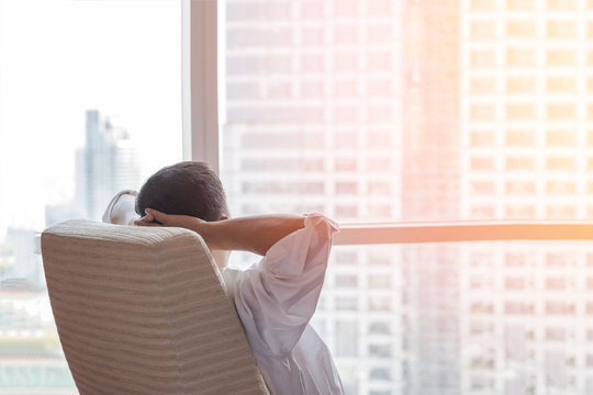 Life-work balance and city lifestyle concept of business man relaxing, take it easy in office room resting with thoughtful mind thinking of living quality looking forward to urban scene