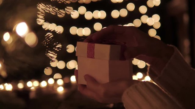 Woman open the gift box with golden light magic on bokeh lights background.