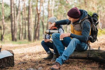 Fototapeta premium father and son drinking tea in forest