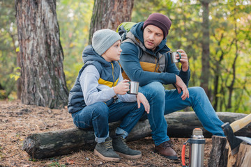 father and son drinking tea in forest