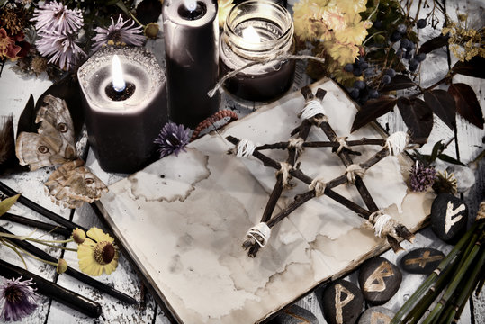 Open book with old empty pages, pentagram and black candles on witch table, toned image