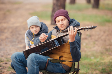 Obraz na płótnie Canvas father and son with guitar in forest