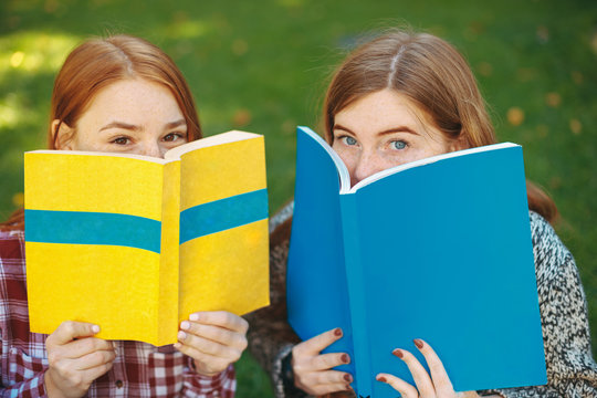 Portrait of cheerful reddish hair girls with freckles and books