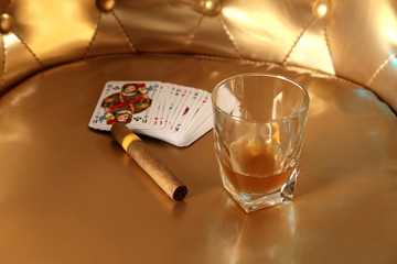 Whiskey im Glas neben Zigarre und Spielkarten