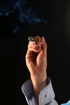 Eine rauchende Zigarre in einer Hand