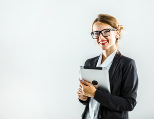 Young caucasian businesswoman with glasses, in a white blouse and a black jacket, is using tablet in the white isolated background