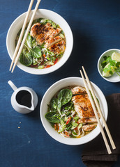 Asian style spicy udon noodle soup with fried chicken on a blue background, top view