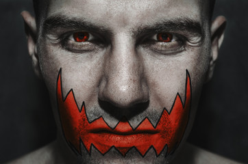 Portrait of a man with a red eye for horror or halloween. Joker orange smile
