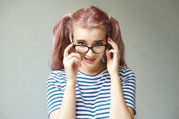 Picture of charming playful pink haired teenage girl with two ponytails and bright make up posing...
