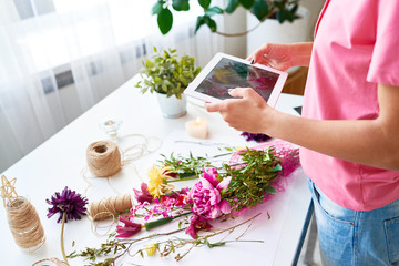 Mid section of unrecognizable young woman taking picture  of flowers using digital tablet to post it on social media