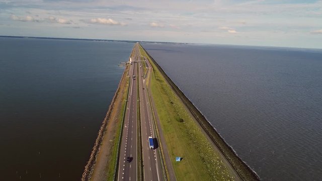 Flying over 32 kilometer long dike called 'Afsluitdijk' along traffic in the Netherlands.