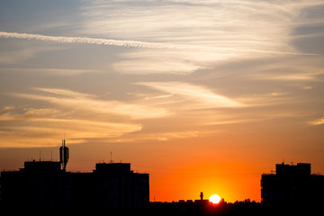 Obraz na płótnie Canvas Buildings silhouettes against dramatic scenic sunset with cloudy fiery sky