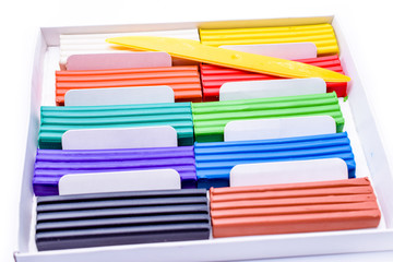 plasticine in a box with a plastic knife on white background