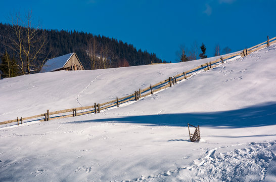 woodshed above the snowy hillside with wooden fence. lovely mountainous rural scenery