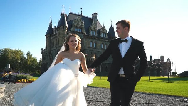 The Bride And Groom Run Near The Old Castle