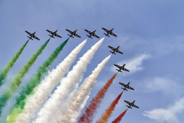 Formation of nine airplanes in the sky at an air show with colorful smoke