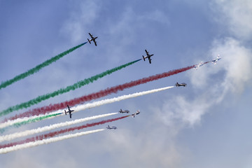 Nine airplanes in the sky at an air show with colorful smoke