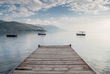 Boats floating near wooden pier in calm Lake Ohrid, Macedonia