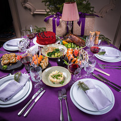 Christmas holiday table purple color with sushi, salad, meat and many delicious dishes with white plates beautiful