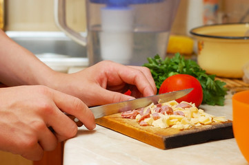 A woman slicing sausage and pizza cheese