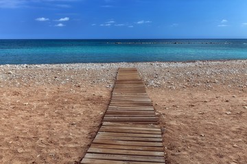 Fototapeta na wymiar A boarded path or wooden boardwalk allowing easy access to and from the sea at Altea in Spain's Costa Blanca