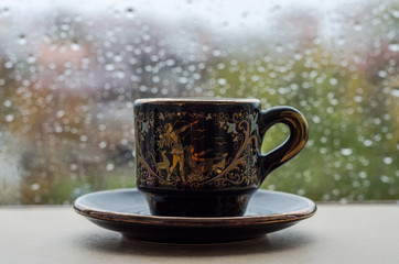 A cup of coffee on the window in the rain