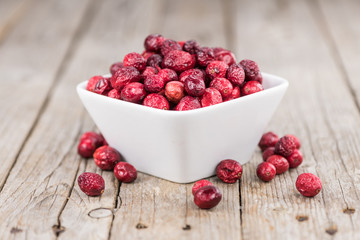 Some fresh Dried Cranberries on wooden background (selective focus; close-up shot)