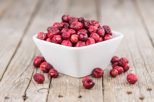 Some fresh Dried Cranberries on wooden background (selective focus; close-up shot)