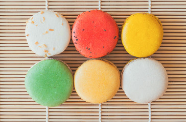 Homemade delicious colorful French or Italian macaron stack on sushi mat in horizontal top view flat lay style for background or wallpaper. Macarons is popular dessert for served with tea or coffee.