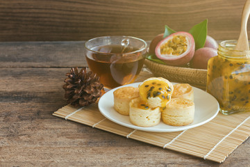 Homemade delicious plain scones serve with passion fruit jam and tea on wood table copy space for background or wallpaper. Scones is traditional English pastry for afternoon tea or coffee break.