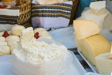 Different types of traditional Romanian cheese on a table in a market.
