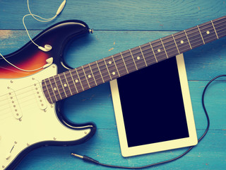 Vintage guitar with earphones on wood