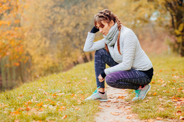 Sad and tired sport woman in autumn park.