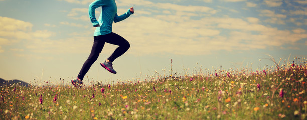 young fitness woman runner running on grassland mountain top