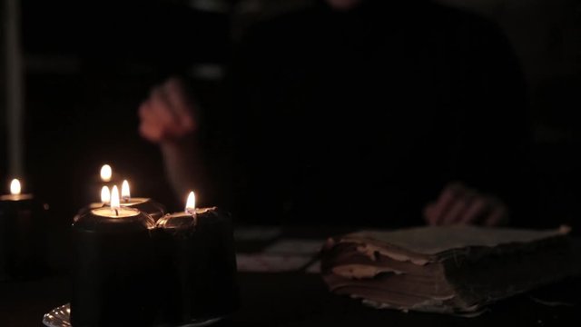 mystical beautiful woman in a black dress, divination on cards by candlelight