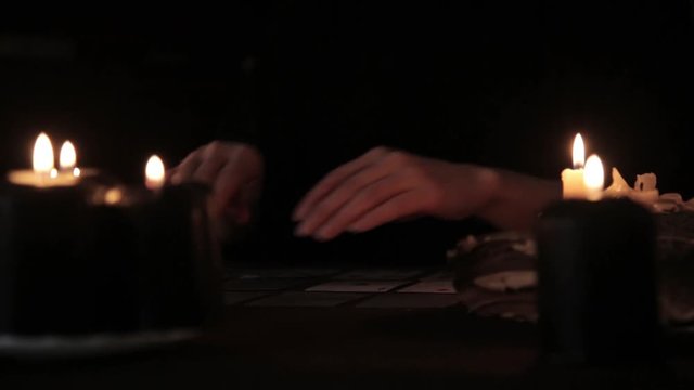 mystical beautiful woman in a black dress, divination on cards by candlelight