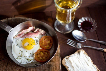 Traditional breakfast with fried egg, toast with cheese and apple juice on wood background.