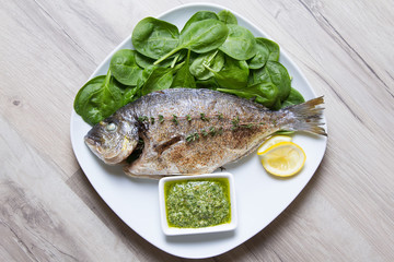 Baked Dorado with spinach and pesto sauce. Close-up. Selective focus.