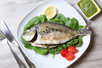 Baked Dorado with spinach and pesto sauce. Close-up. Selective focus.
